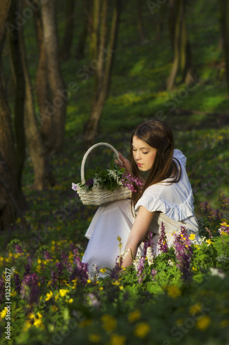 A woman is sitting on a meadow with flowers and enjoying the beauty of nature