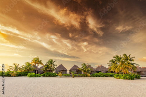 Beach and villas on an island in Maldives at sunset