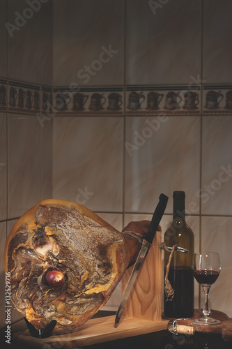 Spanish Jamon Serrano, wooden tabla jamonera, knife, glass and bottle of wine. Food photo concept photo