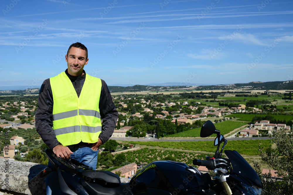 Naklejka premium handsome young man biker with yellow mandatory safety vest under seat of his motorbike
