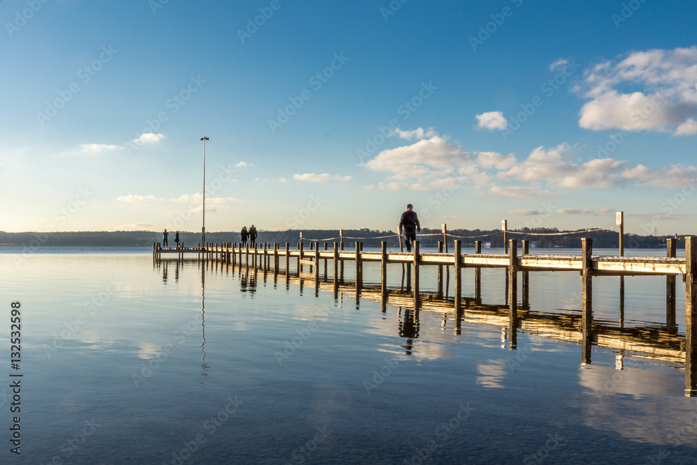 Spaziergänger gehen über einen Steg am See