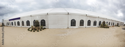 Huge temporary event tent on beach with blustery sky. Horizontal.