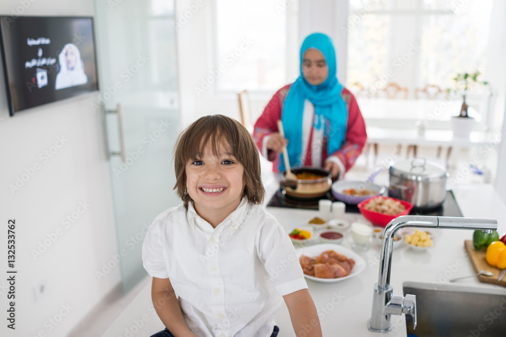 Muslim traditional woman with little son in modern white kitchen Muslim traditional woman with little son in modern white kitchen