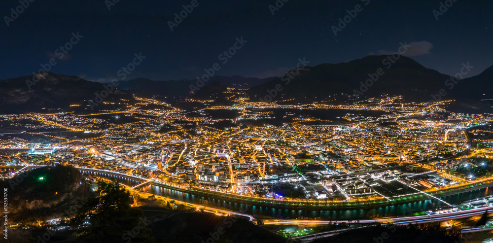 Night skyline of city in mountain valley, Trento, Italy