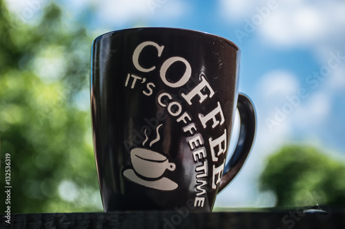 Coffee cup in oudoor. A cup of coffee on wooden table in the garden background.