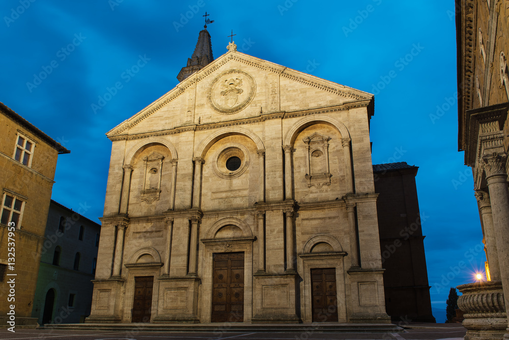 Twilight view of the Pienza Assumption of the Virgin Mary Cathedral with dark blue sky. Facade from white marble. Religious travel destinations background.
