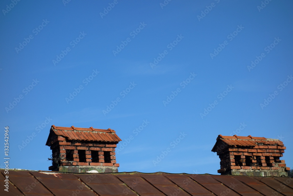 Obraz premium Old brick chimneys on tin roof