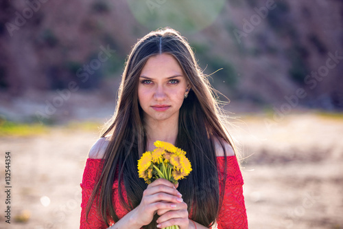 Smiling girl with a bouquet of dandelions. Beautiful smile  long hair   eyes.
