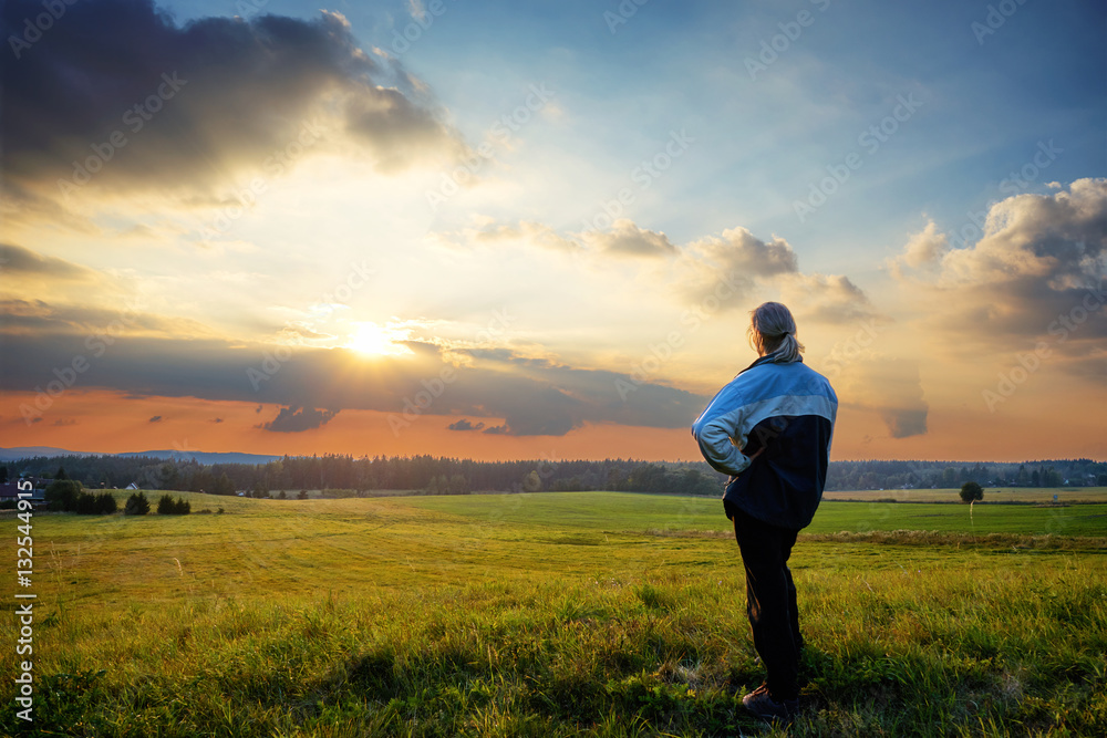Man wistfully watching the sunset on a hill in the countryside Man wistfully watching the sunset on a hill in the countryside