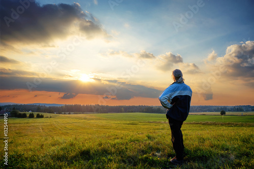 Man wistfully watching the sunset on a hill in the countryside © am