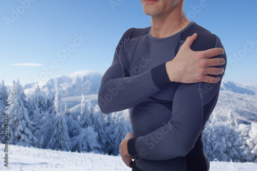 Sport injury, Man with shoulder pain. Pain relief concept in winter background.