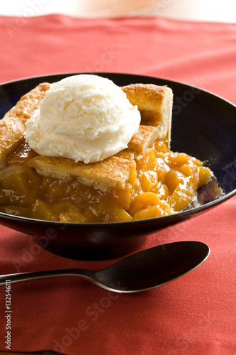 peach cobbler in bowl with ice cream