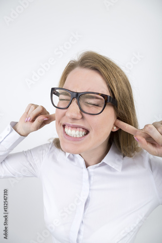 Blond woman in glasses with fingers in ears