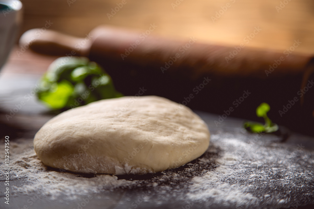 Dough with flour on wooden table, preparing homemade pizza