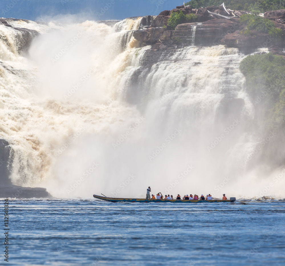 Tourists take pictures of powerful falls with tourists boat in the lagoon of the Canaima national park - Venezuela, South America