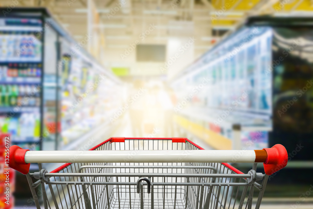 Supermarket aisle with empty red shopping cart Supermarket aisle with empty red shopping cart