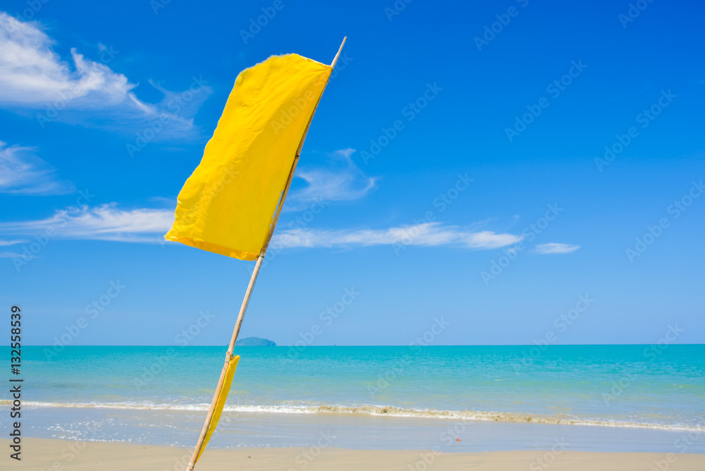 Yellow warning flag on the beach and blue sky at Phuket Thailand