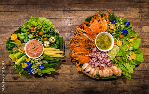 Thai chili sauce or Nam Prik and vegetable set (eggplant,aubergine,lentils,cucumber,corn,zucchini) and Seafood set (shrimp,crab,squid) with Thai sauce On a wooden table , local food Southern Thailand