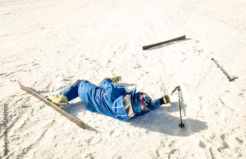 Professional skier after crash accident on skiing resort slope - Winter sport emergency concept with athlete needing help assistance on dramatic trouble situation - Warm sunny afternoon color tones