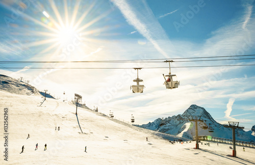 Panoramic view of ski resort glacier and chair lift in french alps - Winter vacation and sport travel concept - Snowboard season opening and people having fun on mountain - Warm afternoon color tone