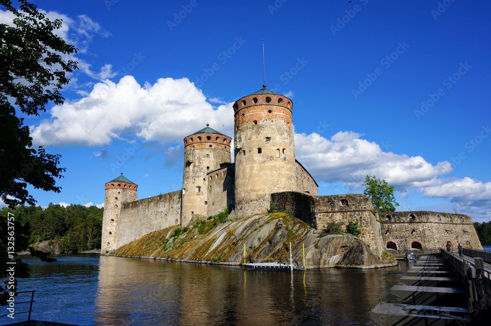 Olavinlinna in Savonlinna, Finland. A castle by a lake surrounded by pine forests.