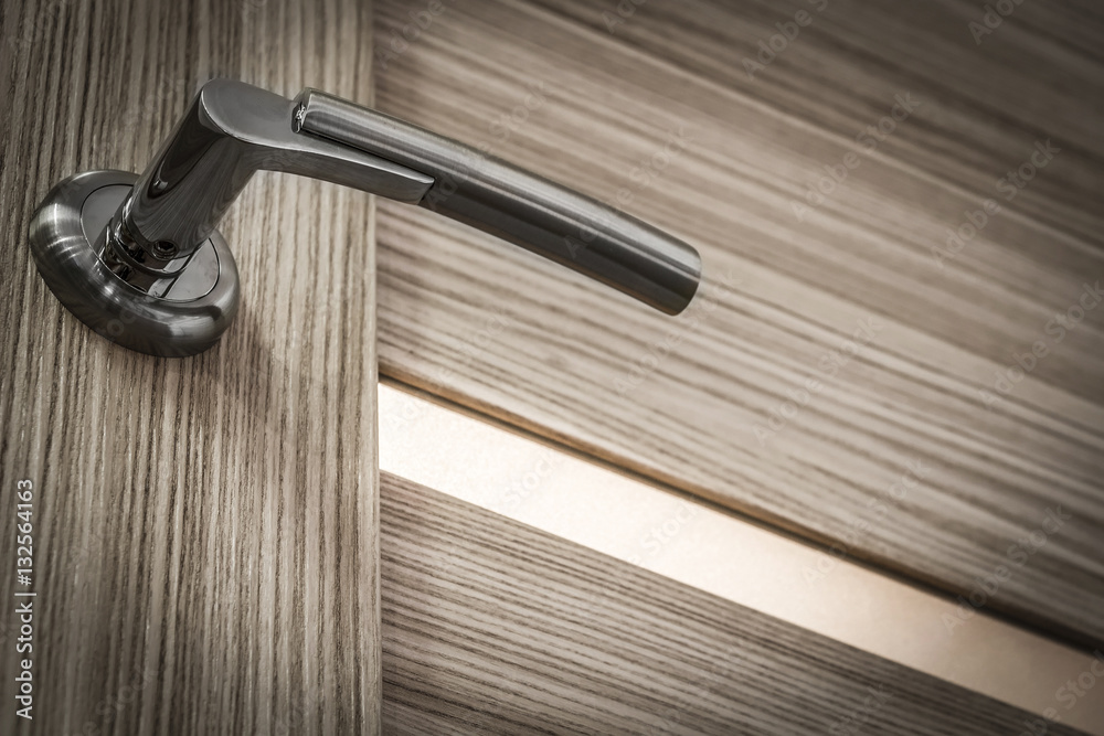 Fototapeta premium Chrome-plated metal handle interior door close-up.