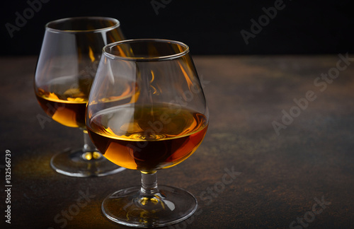 Glass of brandy or cognac on the old rusty background, selective focus, horizontal, copy space