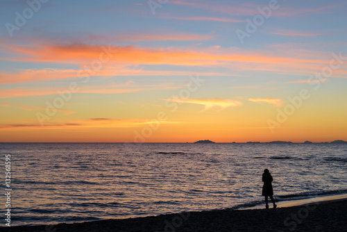 silhouette of woman standing alone on the beach at sunset