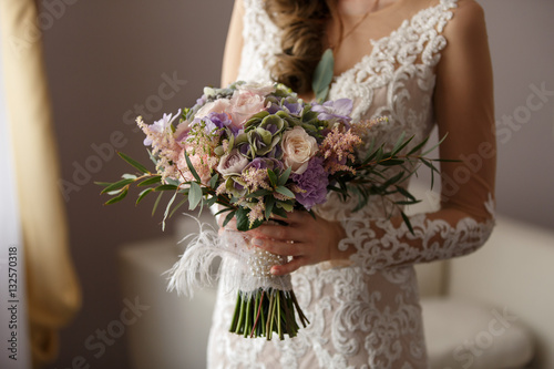 Wedding bouquet, beautiful bride in stylish wedding dress holding bouquet of fresh flowers at wedding day