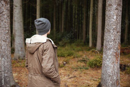 Back view picture of man standing in forest.