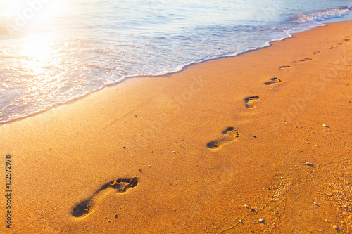 beach, wave and footprints at sunset time