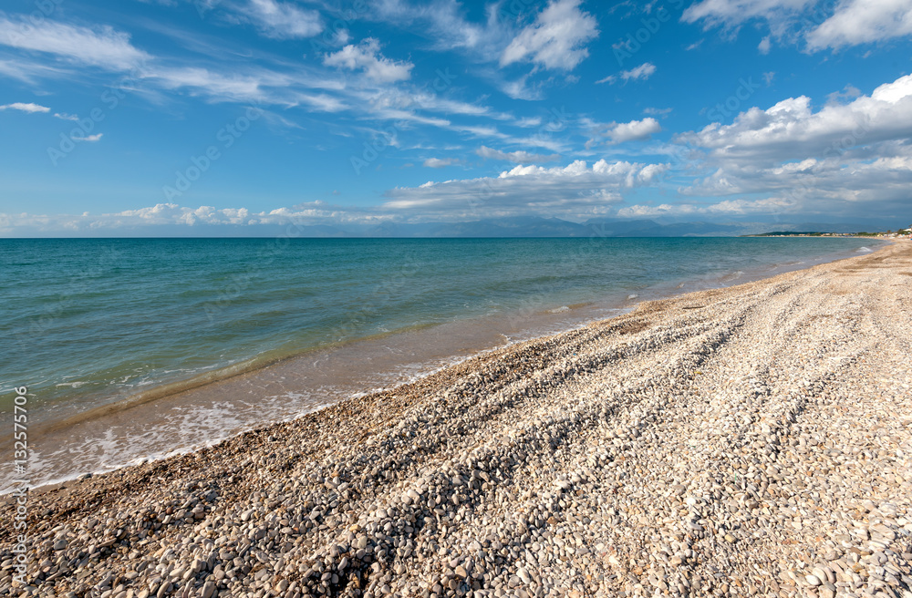 Pebble beach with beautiful view of Albania mountains in Acharavi village on Corfu Island. Greece. Pebble beach with beautiful view of Albania mountains in Acharavi village on Corfu Island. Greece.