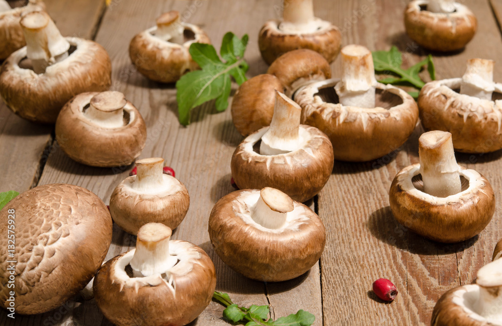 Fresh mushrooms with leaves of arugula on wooden background Fresh mushrooms with leaves of arugula on wooden background