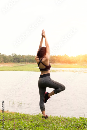 young woman practicing yoga exercises outdoor in park, relax in