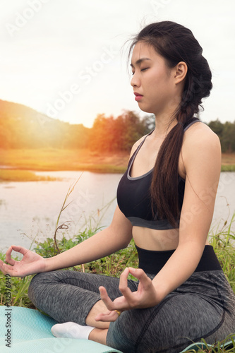 young woman meditates while practicing yoga outdoor in park,  re