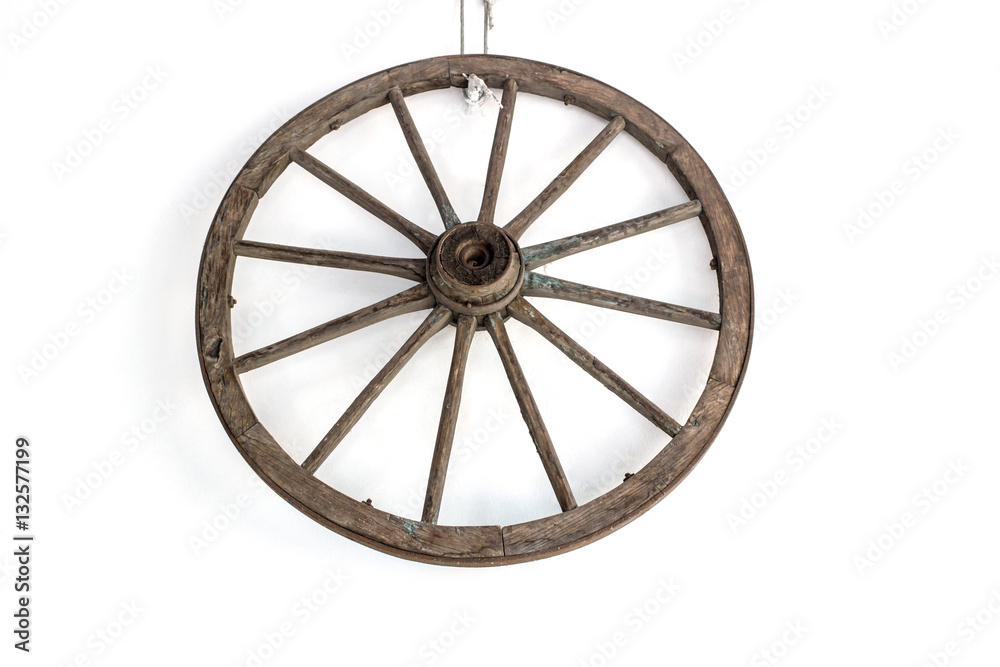 Vintage carriage wheel hang on the white wall / Old wooden wheel / Old wheel hang on the white wall background.