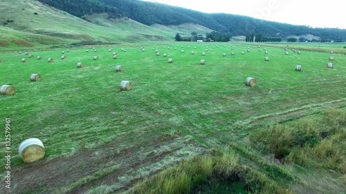 Fast backward fly-by very low over hay bales scattered in green field photo