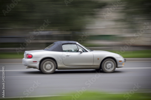 Cabriolet car racing on road. Convertible with a closed top rushing down the road. Everything is blurred. © OlegOk