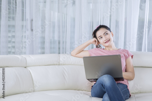 Pensive woman with laptop at home