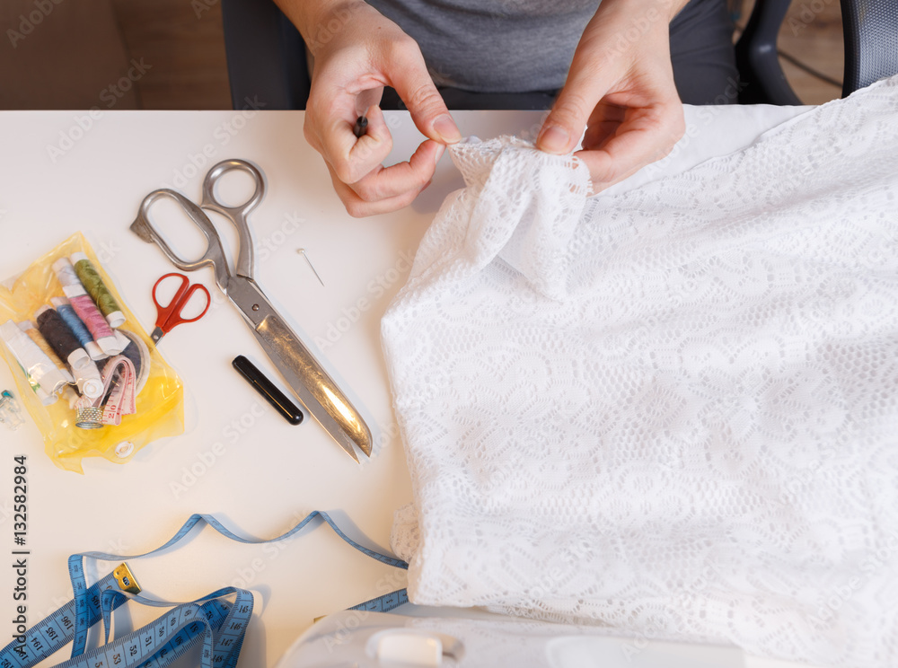 Fototapeta premium Seamstress unrips fabric near sewing-machine