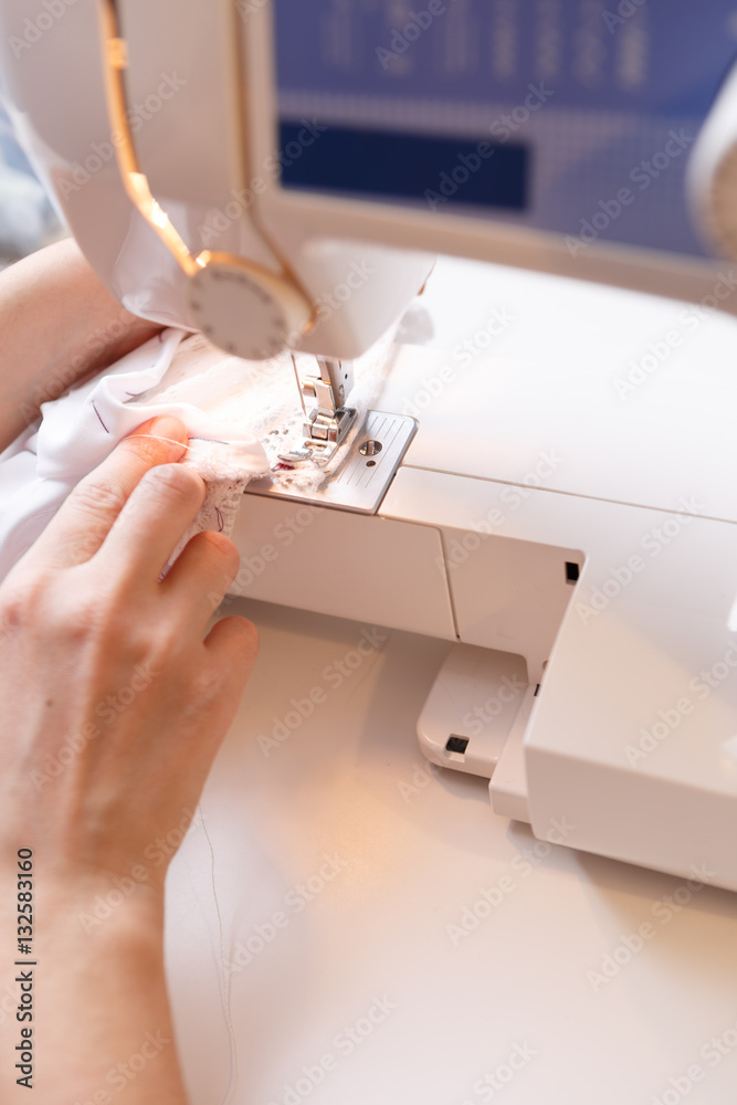 Seamstress sewing white cloth close-up