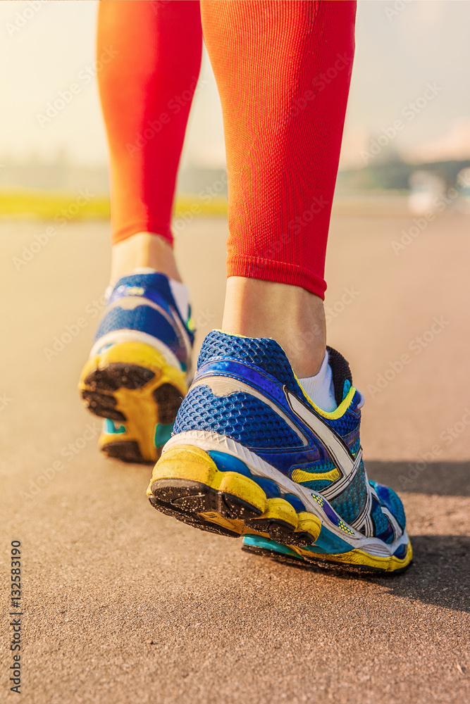 Running sport. Man runner legs and shoes in action on road outdoors at sunset.