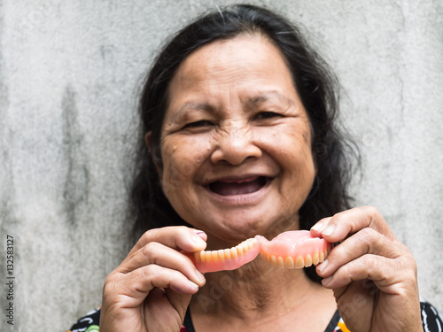 Old thai woman holding false teeth