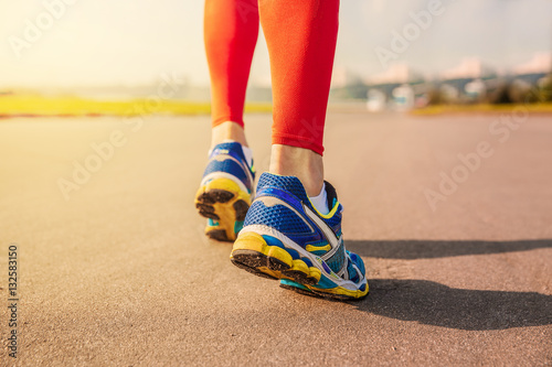 Running sport. Man runner legs and shoes in action on road outdoors at sunset.