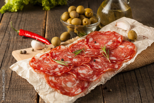 Chorizo sausage and salami, thin cut. spanish salami on the wood background with spices, paprika, pepper. Spicy food. Chili.