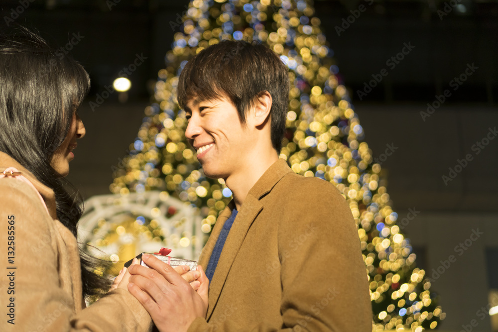 カップル 恋人 デート クリスマスイルミネーション背景 プレゼントを渡す Foto De Stock Adobe Stock