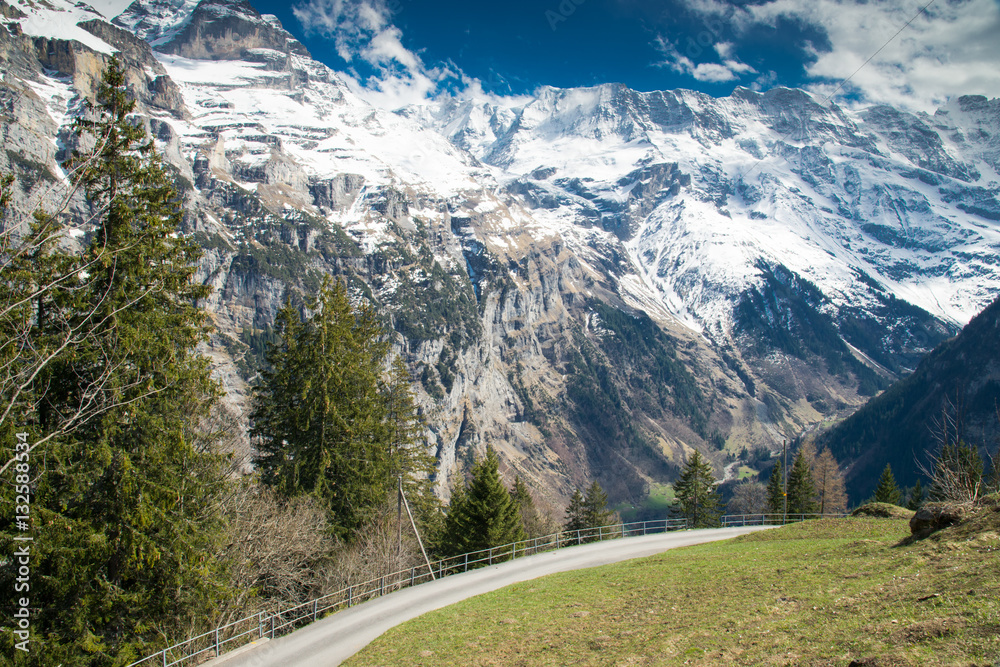 The Snow-covered Swiss Alps in background and Green field at Murren Village, Jungfrau region, Switzerland - April, 2016 The Snow-covered Swiss Alps in background and Green field at Murren Village, Jungfrau region, Switzerland - April, 2016