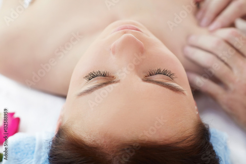 Beautiful young woman lying while massage therapist massaging her shoulders. Total relaxation.
