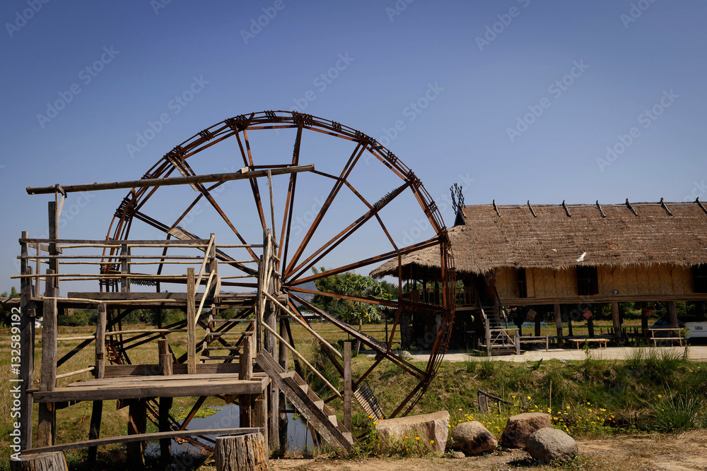 Wood turbine beside rice field.