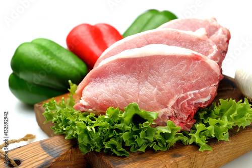 raw pork steaks, lettuce on a cutting board
